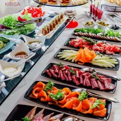 A long, elegant table arrangement featuring a variety of cured meats like salami and prosciutto, smoked salmon, and fresh salads. The linear setup is perfect for allowing guests to move along and sample different items easily.