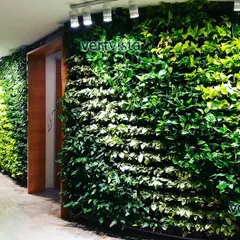 An indoor vertical garden in a commercial building lobby, designed with plants that thrive in low light. The built-in lighting makes the green wall a stunning feature.