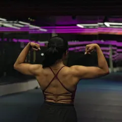 A powerful back-flex pose from my female client. This demonstrates the strength and muscle definition she built through our personalized training program.