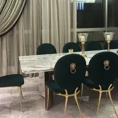 A statement in luxury dining. These custom emerald green velvet chairs feature bold lion head knockers and sculptural gold legs, paired with a substantial marble-topped table. This set was created to be the centerpiece of a grand dining space, reflecting our commitment to opulent and personalized design.
