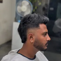 A side profile of a textured mohawk, which is a variation of the modern mullet. The hair is kept longer along the center of the head, creating a spiky, eye-catching silhouette.