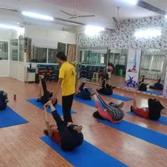 An instructor guides students in Pawanmuktasana (Wind-Relieving Pose). We maintain small batches to ensure every student gets personal attention and corrections, which is crucial for learning to teach safely.