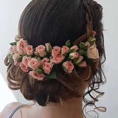 A soft and romantic updo featuring a crown of fresh pink roses. This is a lovely choice for a daytime event or an engagement party.