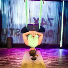 A bound angle pose, or Baddha Konasana, performed while inverted in the aerial hammock. This variation allows gravity to help deepen the stretch in the hips and inner thighs while also providing a gentle spinal traction.