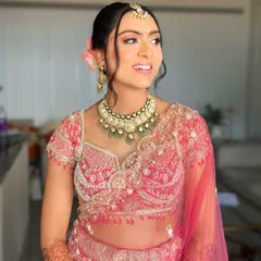 For this bride's pastel lehenga, I crafted a soft and romantic low bun. A few loose, face-framing tendrils and fresh flowers add a touch of modern grace to the traditional bridal hairstyle.