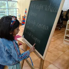 Reading the recipe from the board is the first step in our baking lesson. This integrates practical life with literacy, showing children how reading is a useful tool in everyday activities.