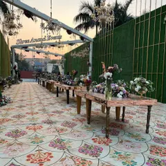 A long dining table setup in an outdoor venue at sunset, showcasing the beautiful floral arrangements and chandeliers before the night begins.