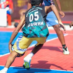 A low-angle shot of a player executing a crossover dribble. The action at the Junior Basketball League is fast-paced and exciting.
