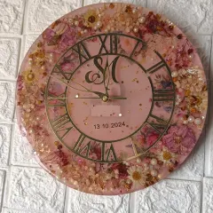 A top-down shot of the pink floral clock, highlighting the couple's monogram and wedding date at the center.