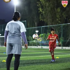 A female coach guides a young player during a drill. We believe in the importance of female role models in coaching and are proud to have them as part of our team, mentoring the next generation.