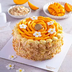 Our signature Fresh Cream Mango Cake, adorned with a beautiful rosette of hand-sliced Alphonso mangoes and delicate sugar flowers. This cake is a celebration of seasonal perfection, with toasted almonds adding a delightful crunch.