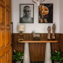 The entryway at Villa Shai sets a tone of rustic elegance, featuring a console table with concrete-finish legs and a wooden top, adorned with tribal art and artifacts. This space received an Honourable Mention at the International Design Awards (IDA).