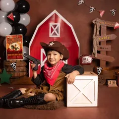 This four-year-old is all smiles, posing with his toy gun in our fun cowboy and barnyard themed shoot.