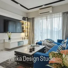 A closer look at this modern living room highlights the interplay of light and shadow. The track lighting on the ceiling is a functional design choice that allows for directed light, while the sheer curtains diffuse natural light beautifully. The bold blue sofa acts as the perfect anchor for the room's neutral tones.