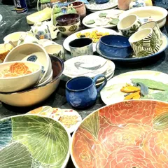 A glimpse of my stall at a pop up, filled with a variety of my handmade ceramics. You can see large floral platters, hand-painted mugs with geometric patterns, and an assortment of bowls, each with its own distinct character and glaze.