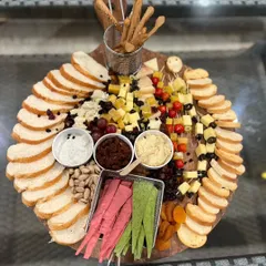 This is our artfully arranged cheese and charcuterie board, a feast for the eyes and the palate. It’s generously packed with artisanal cheeses, crackers, breads, nuts, fresh fruits, and savory dips, perfect for social gatherings.