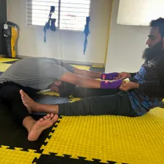 A coach assists a member with a partner stretch, helping to increase flexibility and aid in muscle recovery after a hard workout.