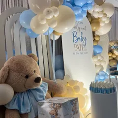 A close-up of a teddy bear themed baby shower, showing a large plush bear next to a "Baby Patel" wishing box, perfect for guests to leave messages for the parents-to-be.