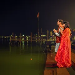 Standing at the edge of the Ganga at night, the couple offers a prayer together. The stillness of the water and the distant lights create a deeply spiritual and peaceful atmosphere for this pre-wedding shot.