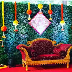 A vibrant backdrop combining a natural green wall with traditional marigold hangings and brass lamps. This fusion design is perfect for a Mehendi or Sangeet ceremony, blending modern and ethnic elements beautifully.