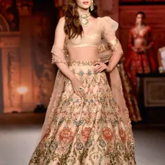 A full-length shot of Kriti Sanon on the runway, showcasing the beautiful flow and intricate floral embroidery of her designer lehenga.