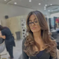 A beautiful shot of a subtle color refresh. The soft, face-framing highlights and layered cut create a modern look, while the gloss treatment adds incredible shine and health.