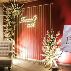 A stylish photo corner at the anniversary event, featuring a neon sign, a comfortable wingback chair, and floral arrangements. We design these spaces to encourage guest interaction and create lasting memories.
