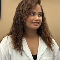 A happy client with her newly colored and styled curls. The color adds warmth and vibrancy, making her curls look healthy and full of life.