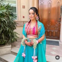 A bride ready for her Mehendi ceremony with her hair in a textured ponytail, adorned with floral jewelry. This style is practical for the event while still looking festive and beautiful.