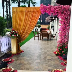 We love creating unique entrances like this one, which combines traditional golden drapes with modern, vibrant pink blossom trees. It sets a beautiful and intriguing tone for the event inside.