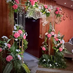 A beautiful entrance arch decorated with pink and white carnations and hanging crystal strings. This design creates a delicate and romantic passageway for guests entering the celebration.