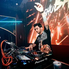 In the zone, mixing tracks at a packed club. This shot captures my focus and technical skill on the Pioneer DJ decks, with custom visuals on the screen behind me.