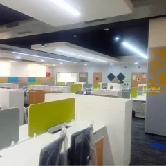 A closer look at the workstation setup in a modern open-plan office. The cubicles feature lime green and grey privacy screens, adding a touch of color while maintaining a professional look. This design balances collaboration with individual focus areas.