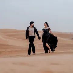 A romantic walk through the endless dunes of the Dubai desert. The simplicity of the black outfits against the golden sand creates a powerful and timeless image of togetherness.