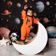 This little explorer is lost in space and loving it, balancing on the moon with a big, happy smile.