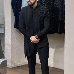 Full view of the black draped indowestern set. The combination of the sharp tailoring and the fluid drape creates a powerful silhouette, perfect for a cocktail party or sangeet.