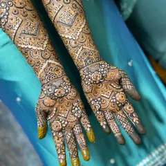 The palms of the bride, showcasing the intricate detail work. This traditional Indian mehendi style fills the hands with flowers, paisleys, and geometric patterns.