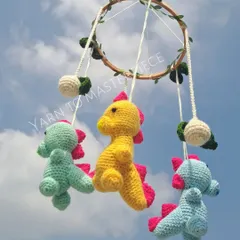 A playful dinosaur-themed cradle mobile. Three friendly dinosaurs in bright colors hang from a leafy hoop, ready to spark your baby's imagination.