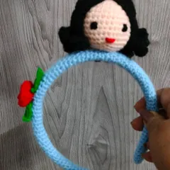 This is my Snow White inspired hair band. I crocheted her little face and attached it to a comfortable blue band with a small red rose. It is a unique handmade accessory for any little princess.