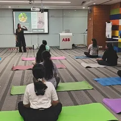 A group of employees at ABB seated in a simple cross-legged position, listening intently during a mindfulness workshop. Creating a calm and focused environment is possible even in an office.