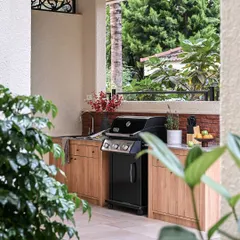 This is the outdoor kitchen I designed for the Modern Spanish Home, located in a covered arched gazebo. It's fully equipped for barbeque nights and features warm wood cabinetry and a durable granite countertop.