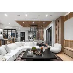 This open-plan living and dining area is defined by its clean lines and sophisticated material palette. The white sectional sofa and wood-slatted ceiling add texture and comfort to the modern design.