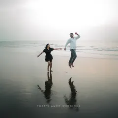 A fun, high-energy shot of a couple jumping for joy on the beach. Their reflections in the wet sand add a beautiful symmetry to this candid moment.