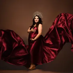 A regal and powerful maternity portrait. The combination of a flowing red gown and a delicate crown creates a truly majestic look, celebrating the queen that every mother-to-be is.