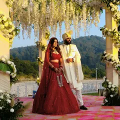 A stunning couple portrait at their riverside wedding in Jim Corbett. The mandap, adorned with cascading white wisteria, creates a dreamy backdrop against the natural landscape.