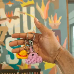 A close-up of handmade Amigurumi keychains, including a pink octopus and a yellow hat. These small, charming projects are perfect for beginners.