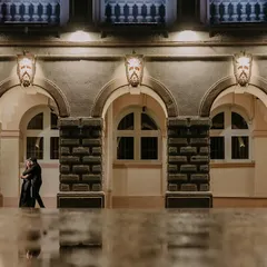 A couple embraces under the arches of a classic building, their figures reflected in the wet ground after a monsoon shower. This shot uses architectural framing and reflections to create a moody, artistic pre-wedding portrait.