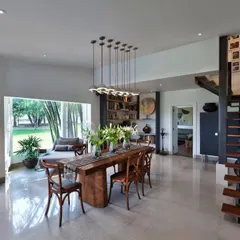 In the Aishbagh dining space, a table made from a single slab of teak from Borneo grounds the room with its strong presence. Above it, a cluster of modern pendant lights adds a contemporary touch, illustrating our love for mixing raw materials with refined design.