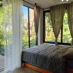 The bedroom in this Coorg cabin is surrounded by floor-to-ceiling windows, immersing guests in the natural landscape. This is the kind of unique experience that earns great reviews.