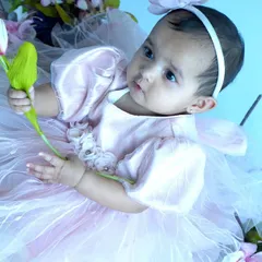 A sweet baby girl in a pink tulle dress holds a tulip, surrounded by flowers. This themed baby photoshoot showcases our use of props and soft lighting to create a dreamy atmosphere.
